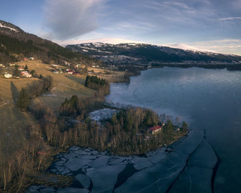 Scenic view of lake by snowcapped mountains against sky