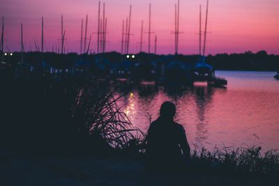 Silhouette man standing by sea against sky at sunset