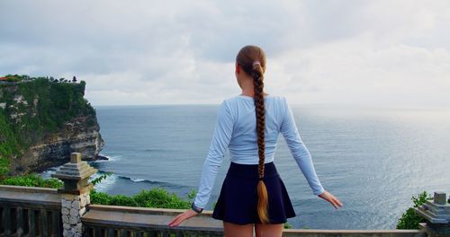 Rear view of woman standing against sea