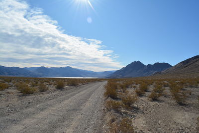 Dirt road amidst desert against sky - race track playa death valley national park