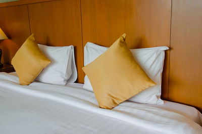 White and yellow pillows arranged on bed in hotel