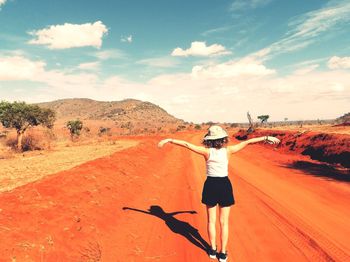Man with arms outstretched on landscape against sky