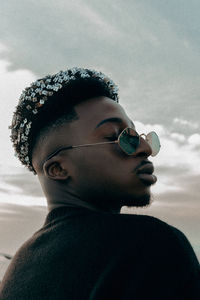 Portrait of young man wearing sunglasses against sky