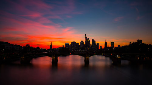 Bridge over river and buildings against sky at sunset financial district frankfurt 