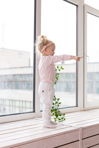 Portrait of young woman standing by window