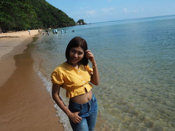 Portrait of smiling young woman standing on beach