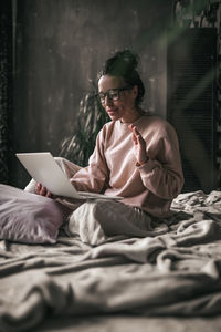 Midsection of man using mobile phone while sitting on bed