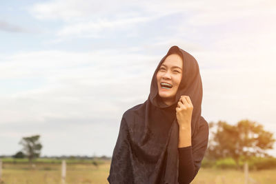 Smiling woman wearing headscarf looking away against sky