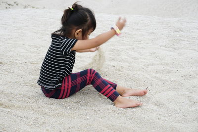 Side view of girl playing with sand at beach