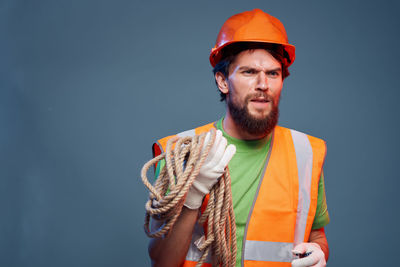 Portrait of man holding hat against gray background