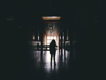 Silhouette woman in dark passage at home