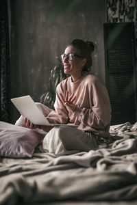 Woman sitting on bed at home