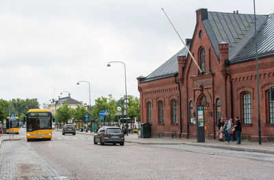 Cars on road by buildings against sky