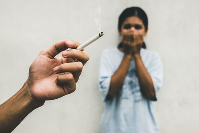 Man is smoking cigarette and woman is covering her face. passive smoking and healthcare