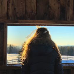 Rear view of woman looking through window