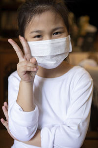 Portrait of girl wearing mask gesturing indoors