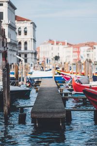 Boats moored on canal amidst buildings in city