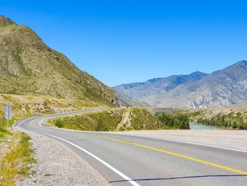 Road by mountain against blue sky