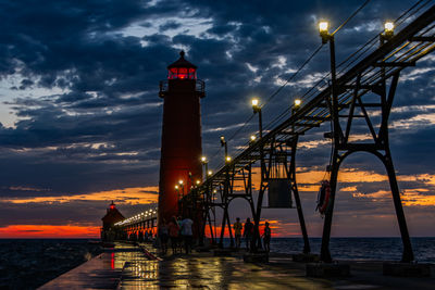 A sunset and storm clouds create dramatic lighting behind grand haven, michigan lighthouse and pier