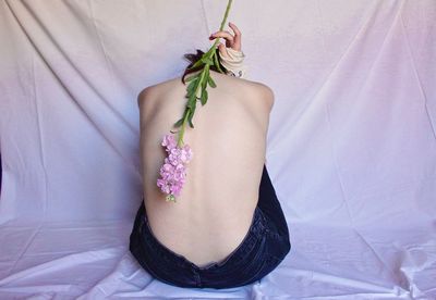 Rear view of woman with pink flower on bed