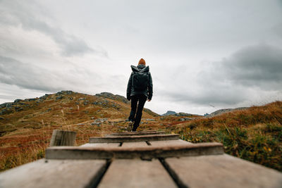 Rear view of woman walking on mountain against sky