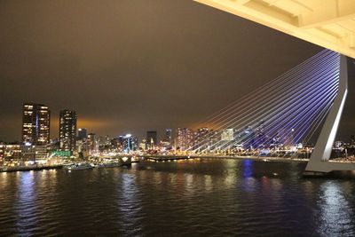 Illuminated city by river against sky at night