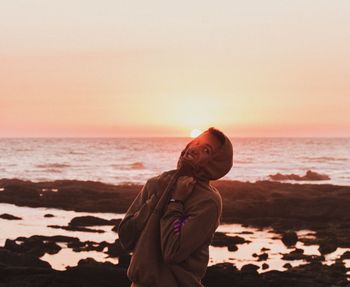 Man standing on beach against sky during sunset