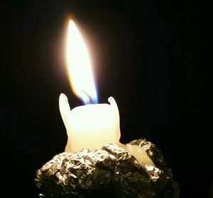 Close-up of lit candle in dark room