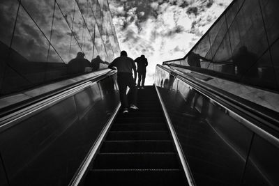 Rear view of people walking on escalator