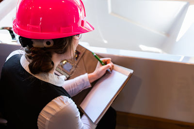 High angle view of engineer writing in diary