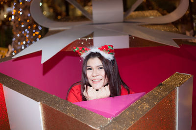 Portrait of smiling woman sitting in gift box during christmas celebration