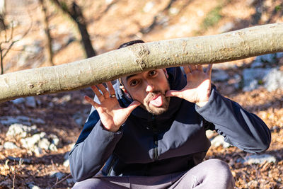 Young man smiling and joking with a fallen tree in the forest in winter