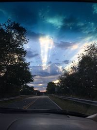 Road amidst trees against sky seen through car windshield