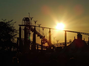 Low angle view of silhouette rollercoaster against sky during sunset