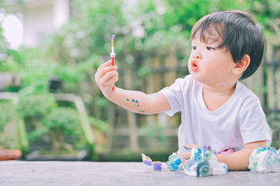 Boy looking away while sitting on toy against blurred background