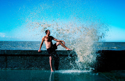 Full length of shirtless man in swimming pool against sea