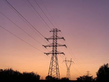 Low angle view of silhouette electricity pylon against sky during sunset