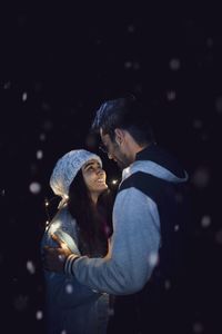 Young couple romancing while standing against sky at night