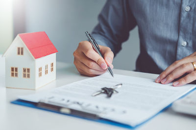 Midsection of man holding paper on table