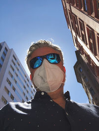 Low angle portrait of man against buildings in city
