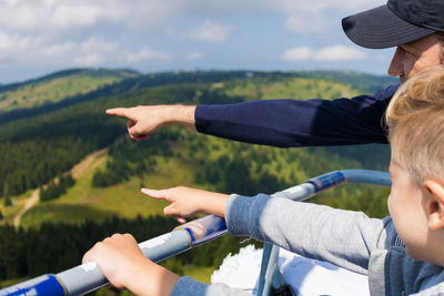 Father and son pointing at mountains from observation point