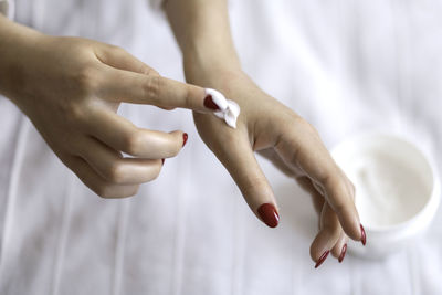 Beautiful groomed woman's hands with cream jar on the blanket. moisturizing cream for soft skin