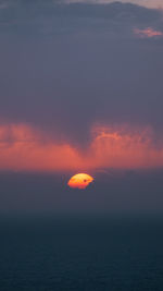 Hot orange sun setting behind clouds and coloring the haze pink 