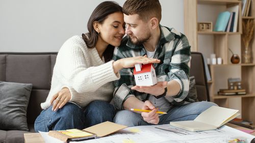 Young couple holding hands while sitting in laptop