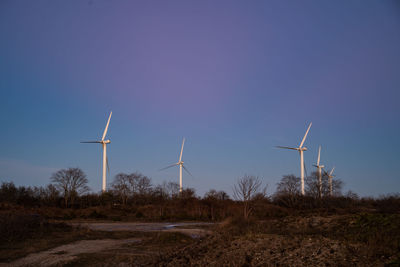 Windmills on field against clear sky