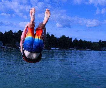 Man wearing multi colored swimming trunks diving in sea against sky