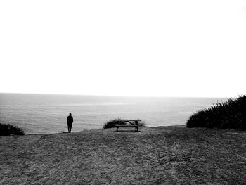 Silhouette man standing on beach against clear sky