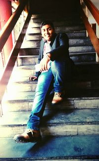 High angle view of young woman sitting on wooden wall