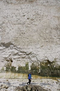 Man walking at beach against chalk cliffs of seven sisters