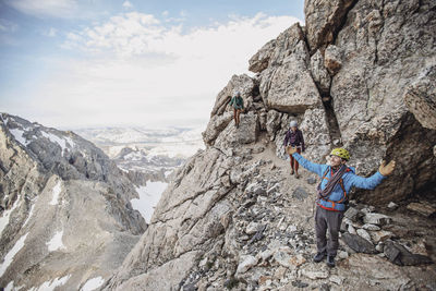 Climbing guide spreads his arms in wonder while taking in the view